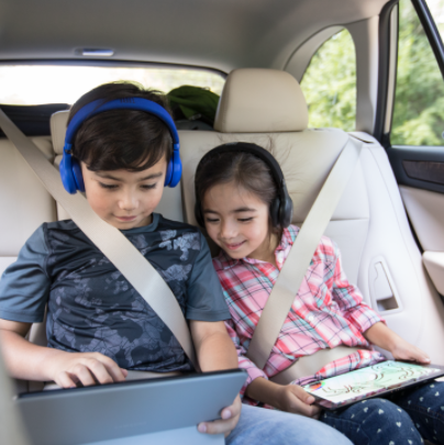 children looking down at tablet in car