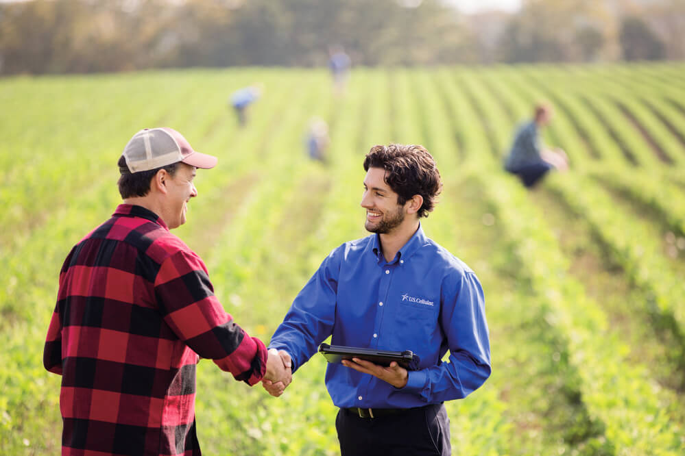 US Cellular representative shaking hands with farmer outside in field