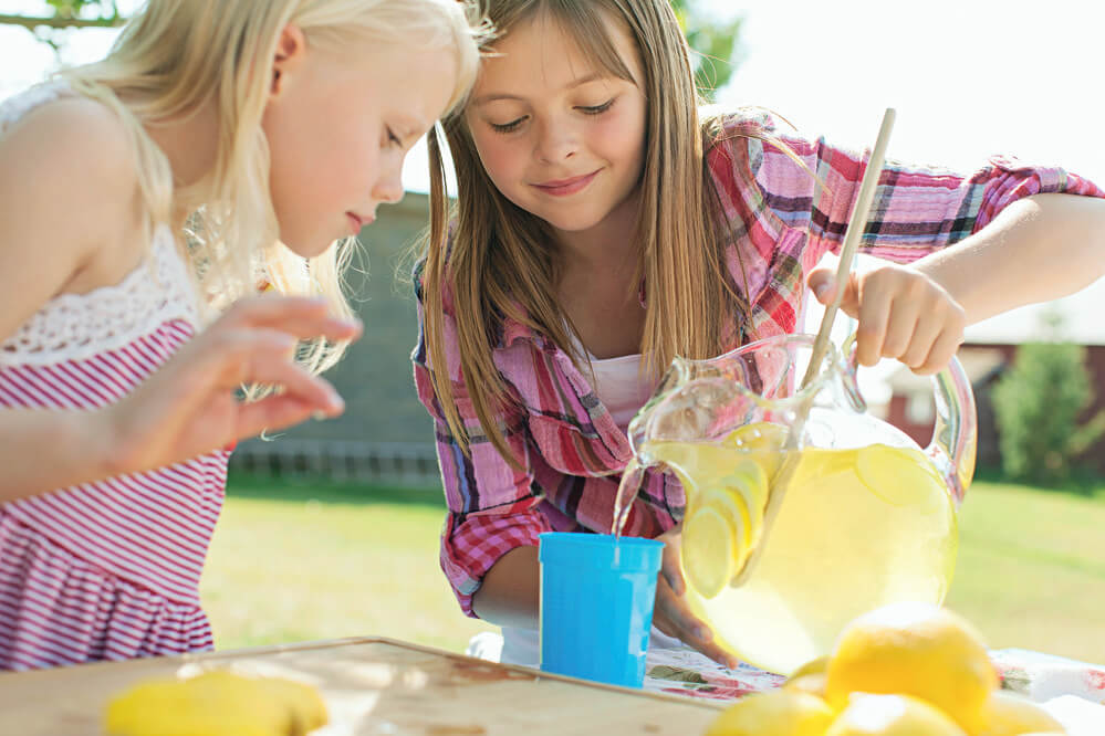two young girls pouring lemonade